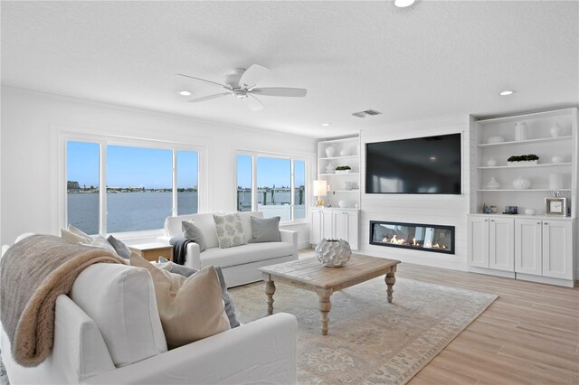 7060 S Shore Dr S, South Pasadena, FL 33707 - living room with ceiling fan, light wood-type flooring, a large fireplace, a textured ceiling, and recessed lighting