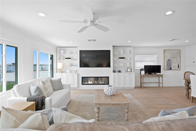 7060 S Shore Dr S, South Pasadena, FL 33707 - living area with recessed lighting, ceiling fan, a fireplace, light wood-style flooring, and crown molding
