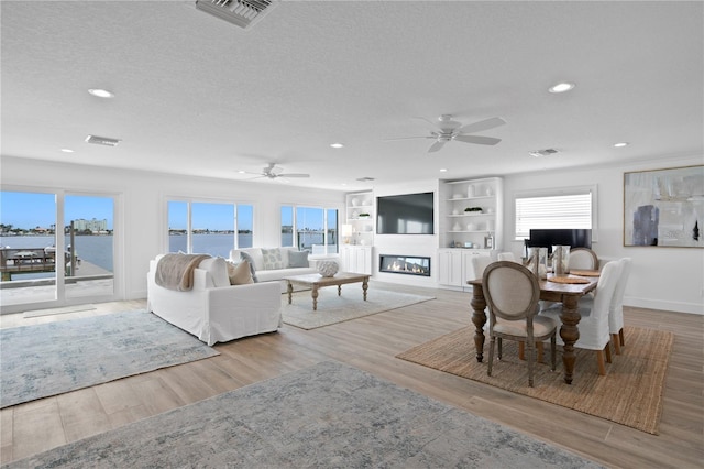7060 S Shore Dr S, South Pasadena, FL 33707 - living room featuring recessed lighting, a ceiling fan, wood finished floors, a textured ceiling, and a glass covered fireplace