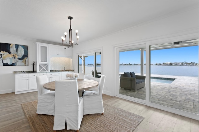 7060 S Shore Dr S, South Pasadena, FL 33707 - dining area featuring crown molding, a chandelier, a water view, and light wood-style floors