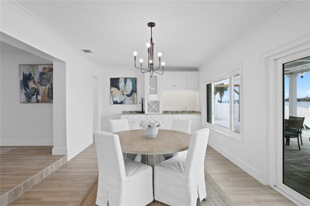 7060 S Shore Dr S, South Pasadena, FL 33707 - dining space featuring a chandelier, healthy amount of natural light, ornamental molding, and light wood-style flooring