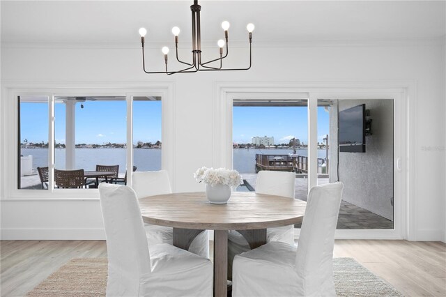 7060 S Shore Dr S, South Pasadena, FL 33707 - dining space with ornamental molding, a chandelier, light wood-type flooring, baseboards, and a water view