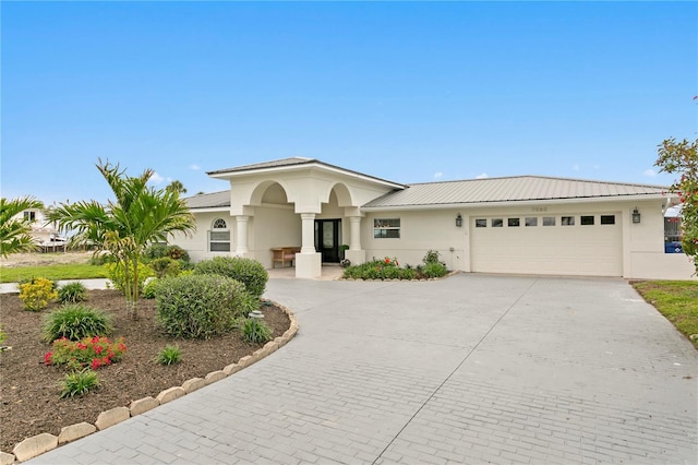 7060 S Shore Dr S, South Pasadena, FL 33707 - view of front of home with curved driveway, stucco siding, an attached garage, and metal roof