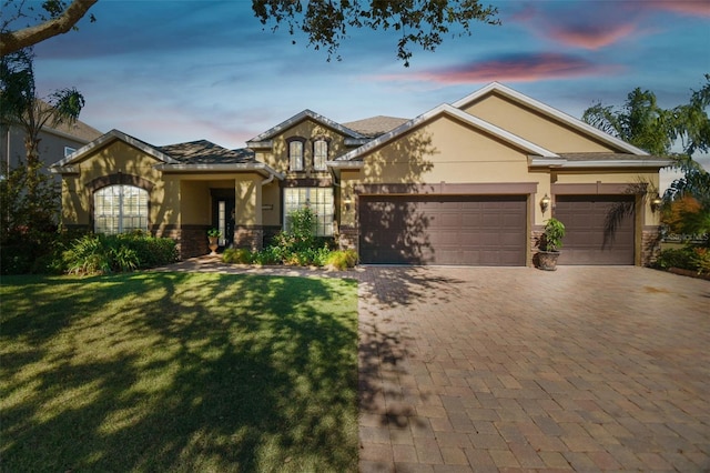 1116 Hillandale Reserve Dr, Tampa, FL 33613 - view of front facade with stone siding, stucco siding, decorative driveway, an attached garage, and a front lawn