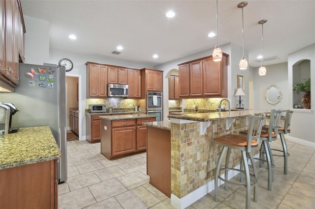 1116 Hillandale Reserve Dr, Tampa, FL 33613 - kitchen featuring appliances with stainless steel finishes, a peninsula, decorative backsplash, light stone counters, and light tile patterned flooring