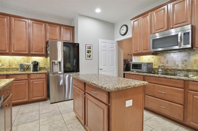 1116 Hillandale Reserve Dr, Tampa, FL 33613 - kitchen with stainless steel appliances, tasteful backsplash, light stone counters, a center island, and brown cabinetry