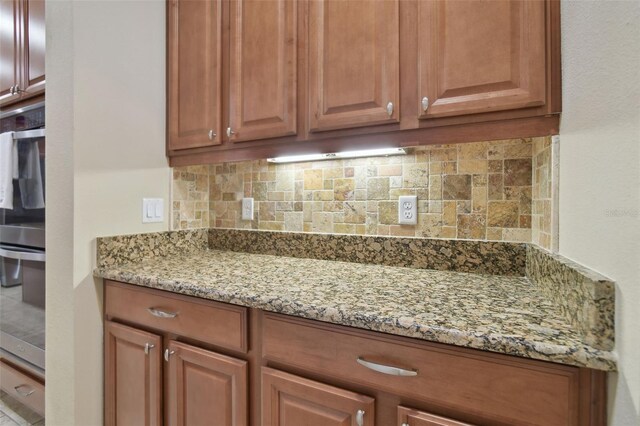 1116 Hillandale Reserve Dr, Tampa, FL 33613 - kitchen with backsplash, light stone counters, and brown cabinets