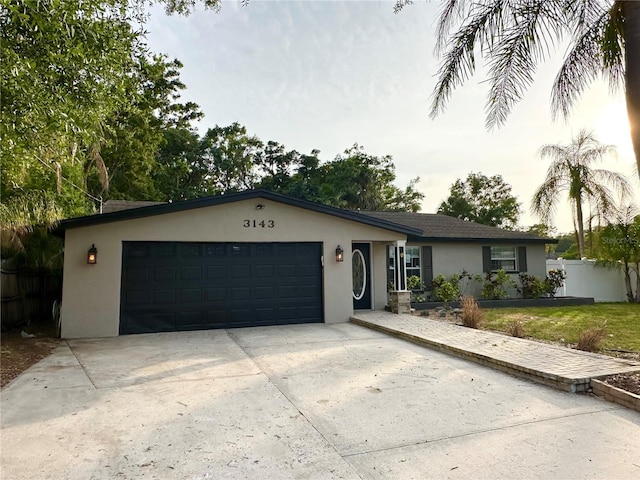ranch-style house with stucco siding, a garage, fence, and driveway
