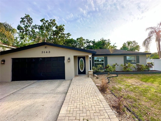 single story home featuring stucco siding, a garage, and driveway
