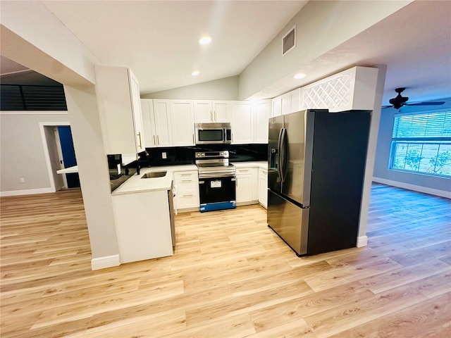 kitchen featuring appliances with stainless steel finishes, light wood-type flooring, white cabinets, baseboards, and a sink
