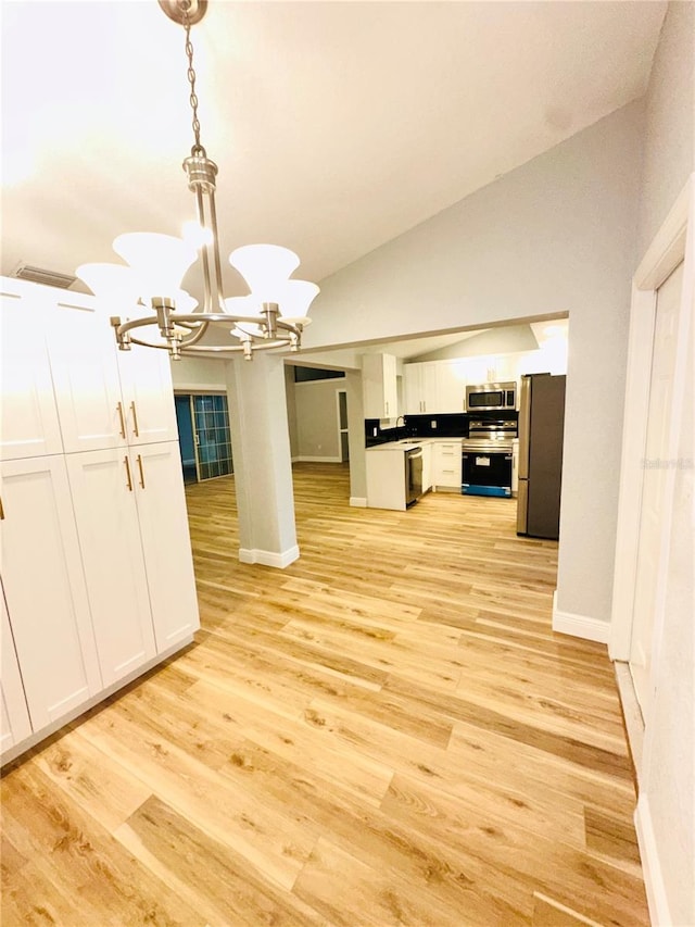 unfurnished dining area with a chandelier, light wood finished floors, baseboards, and vaulted ceiling