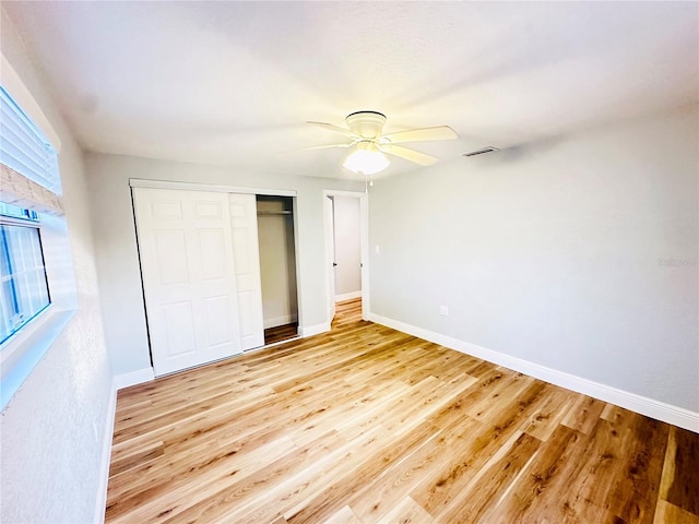unfurnished bedroom with baseboards, a closet, light wood-style flooring, and ceiling fan