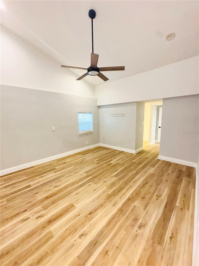 empty room with ceiling fan, light wood-style flooring, baseboards, and lofted ceiling