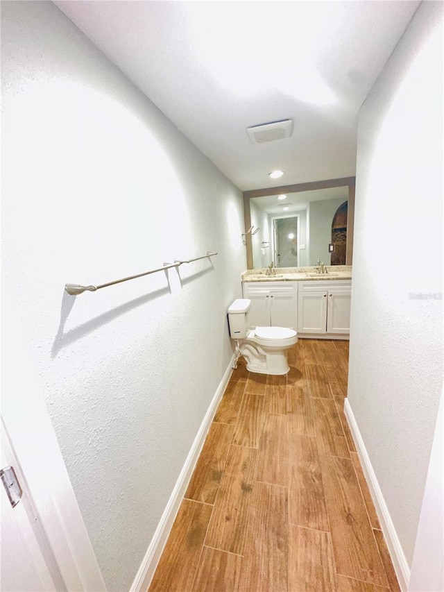 bathroom featuring wood finished floors, toilet, baseboards, and vanity