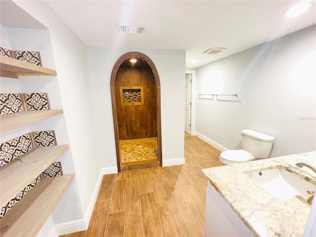 full bathroom featuring wood finished floors, baseboards, vanity, a tile shower, and recessed lighting