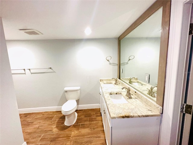 bathroom featuring wood finished floors, vanity, toilet, baseboards, and recessed lighting