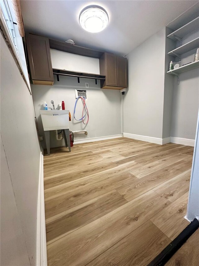 laundry area featuring hookup for a washing machine, cabinet space, light wood-style floors, and baseboards