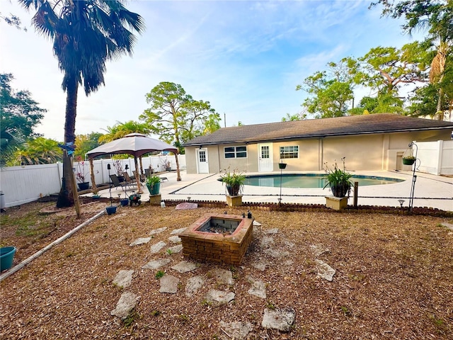 rear view of property with a fire pit, a gazebo, a fenced backyard, and a patio