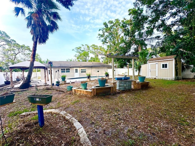 view of yard with a gazebo, a storage shed, an outdoor structure, and fence