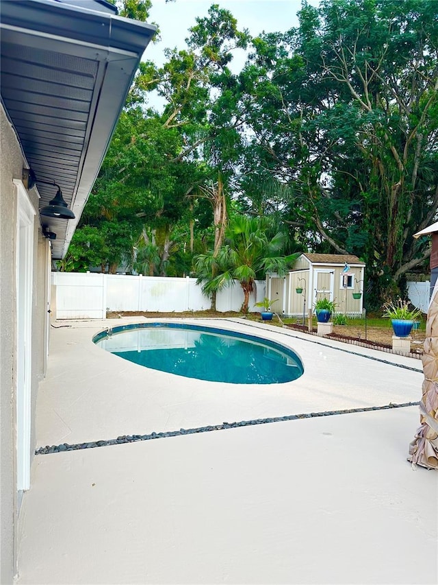 view of swimming pool featuring a storage shed, an outdoor structure, a fenced backyard, and a patio area