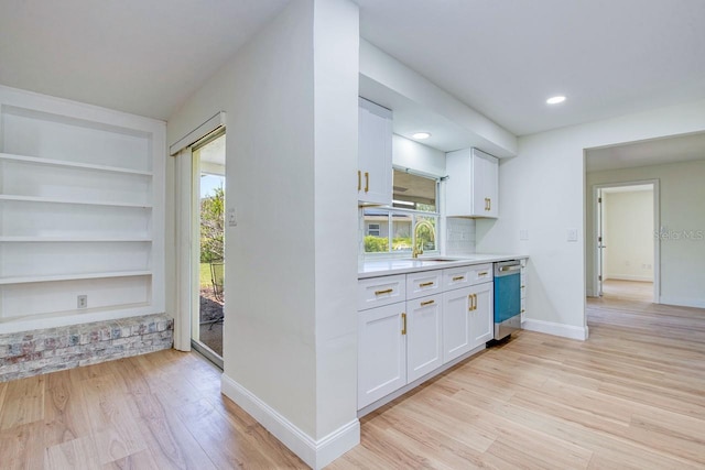 kitchen featuring dishwasher, a sink, white cabinetry, light wood-type flooring, and recessed lighting