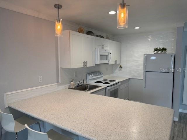 kitchen featuring white appliances, a sink, light countertops, a peninsula, and decorative backsplash