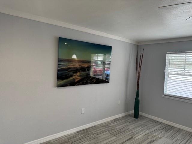 unfurnished room featuring wood finished floors, ornamental molding, and baseboards
