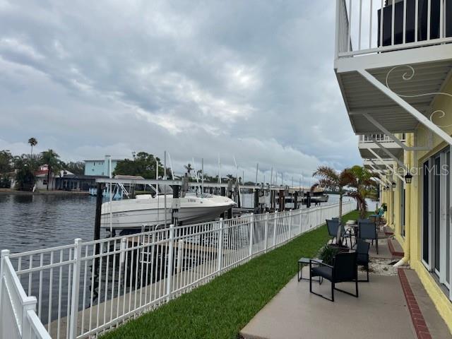 view of yard with a water view, a boat dock, a patio, and boat lift