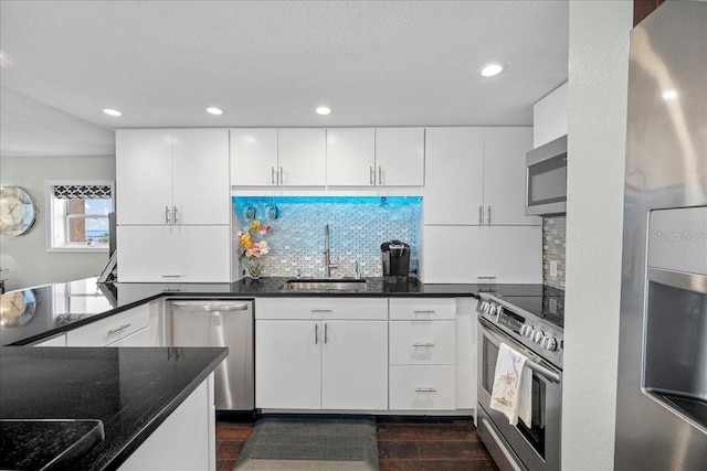 kitchen featuring a sink, stainless steel appliances, dark wood-type flooring, backsplash, and white cabinets