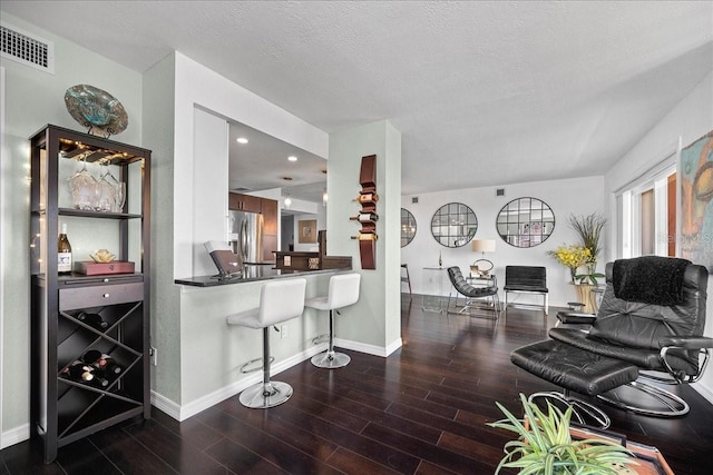 living area with wood finished floors, baseboards, recessed lighting, and a textured ceiling