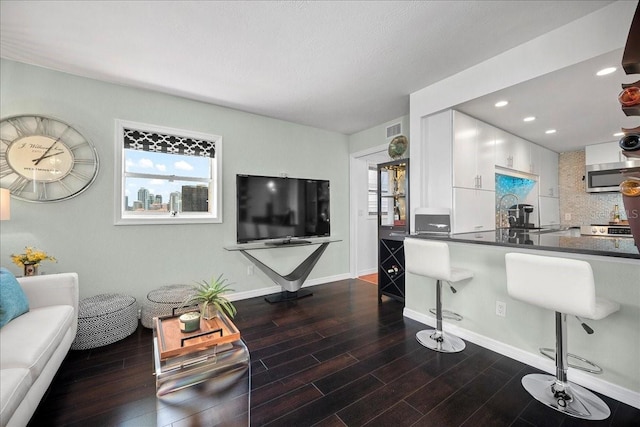 kitchen with appliances with stainless steel finishes, white cabinets, dark countertops, a kitchen breakfast bar, and dark wood finished floors