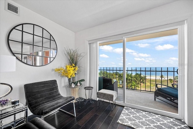 sitting room featuring wood finished floors, a water view, and baseboards