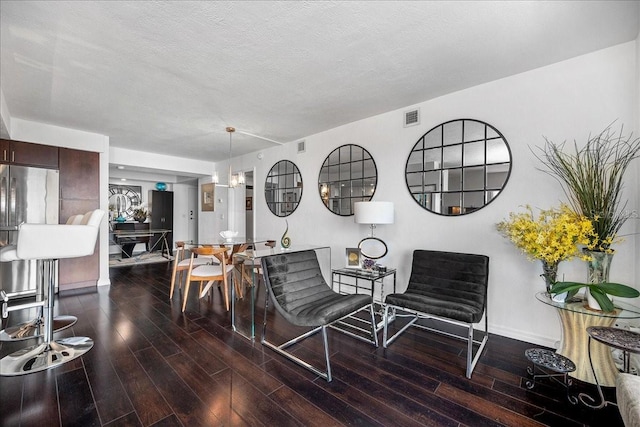 living area with wood finished floors, baseboards, and a textured ceiling