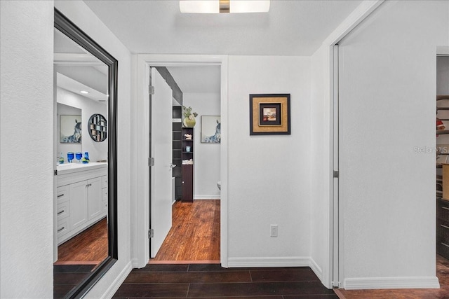 hallway featuring dark wood-type flooring and baseboards
