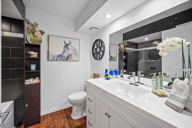 full bathroom with wood finished floors, toilet, vanity, a tile shower, and baseboards