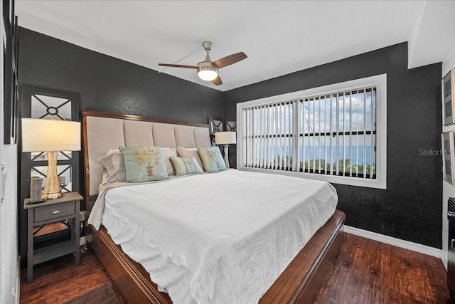 bedroom with wood finished floors, baseboards, a textured wall, and ceiling fan