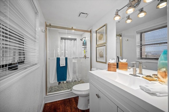 bathroom featuring a stall shower, toilet, vanity, and wood finished floors