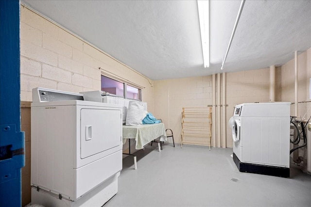 laundry room featuring washer and dryer and concrete block wall