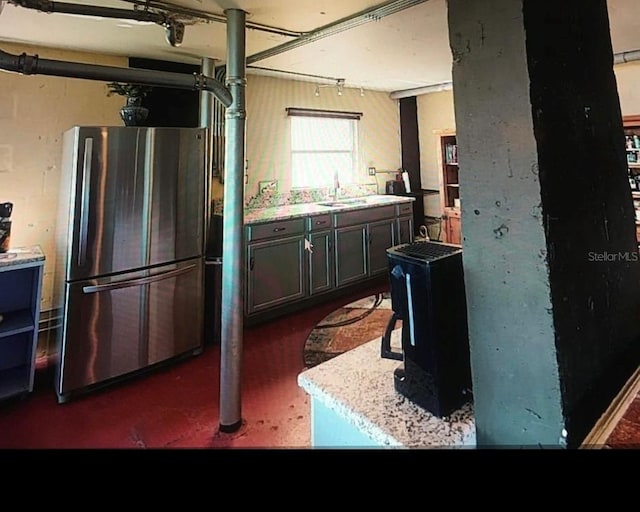 kitchen featuring freestanding refrigerator, a sink, and a wood stove