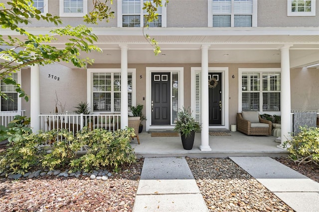 property entrance featuring covered porch and stucco siding