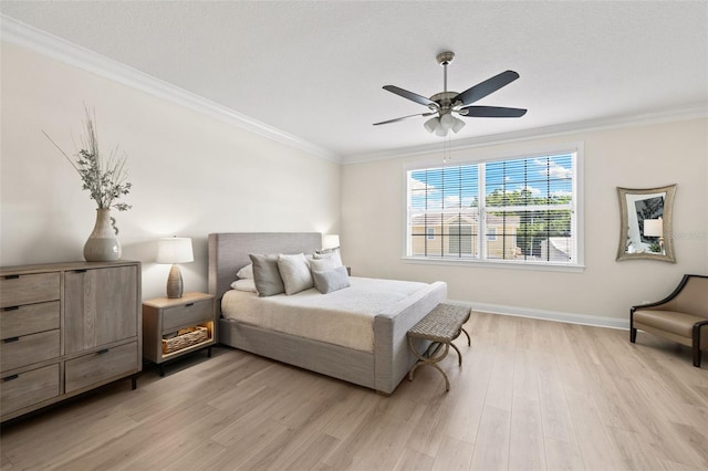 bedroom featuring light wood finished floors, crown molding, baseboards, and ceiling fan