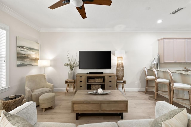 living area with a ceiling fan, ornamental molding, light wood finished floors, baseboards, and recessed lighting