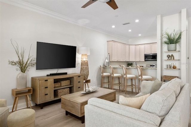 living room with a ceiling fan, crown molding, light wood-style floors, recessed lighting, and baseboards