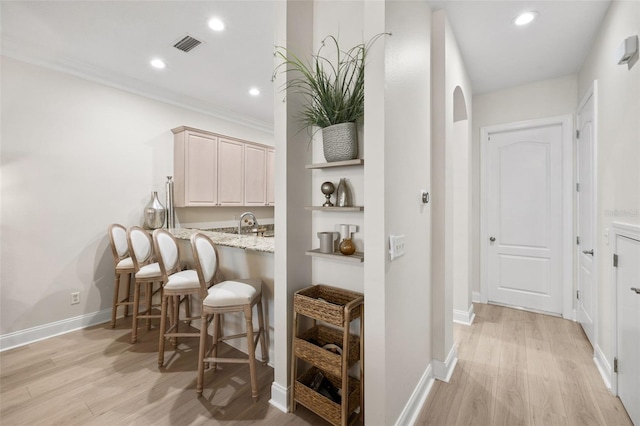bar with light wood-type flooring, recessed lighting, baseboards, a sink, and ornamental molding