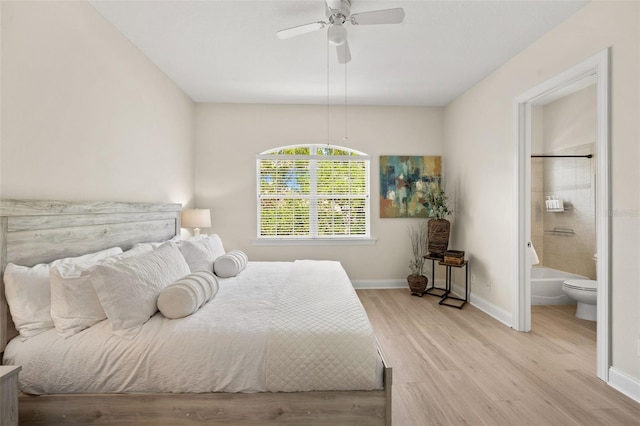 bedroom featuring wood finished floors, baseboards, ensuite bath, and a ceiling fan