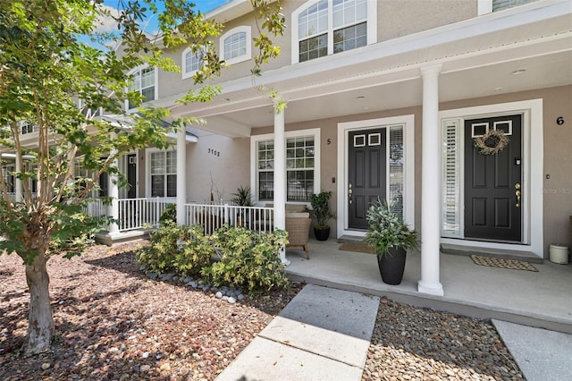 view of exterior entry with a porch and stucco siding