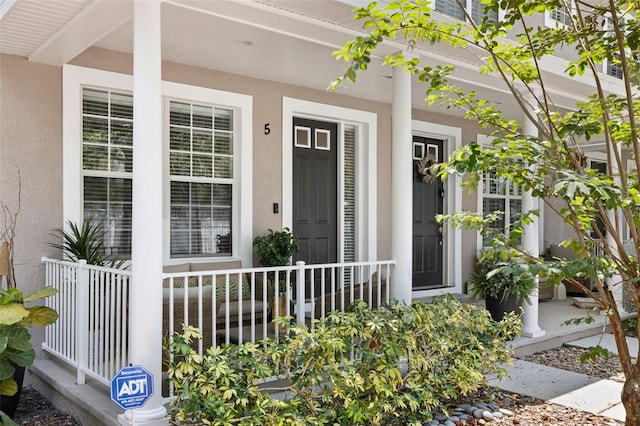 entrance to property featuring covered porch and stucco siding