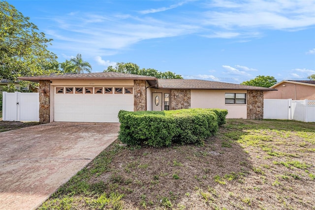 8744 Andros Ln, Port Richey, FL 34668 - view of front of house with stone siding, a gate, an attached garage, and driveway