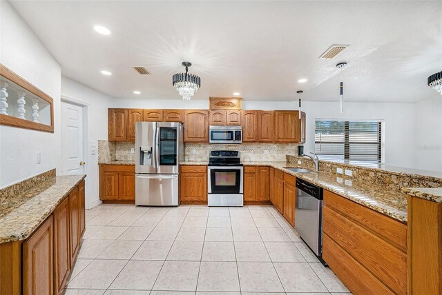 8744 Andros Ln, Port Richey, FL 34668 - kitchen with stainless steel appliances, brown cabinets, tasteful backsplash, a chandelier, and recessed lighting