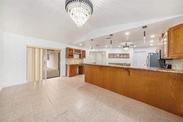 8744 Andros Ln, Port Richey, FL 34668 - kitchen featuring brown cabinets, backsplash, light stone countertops, glass insert cabinets, and lofted ceiling